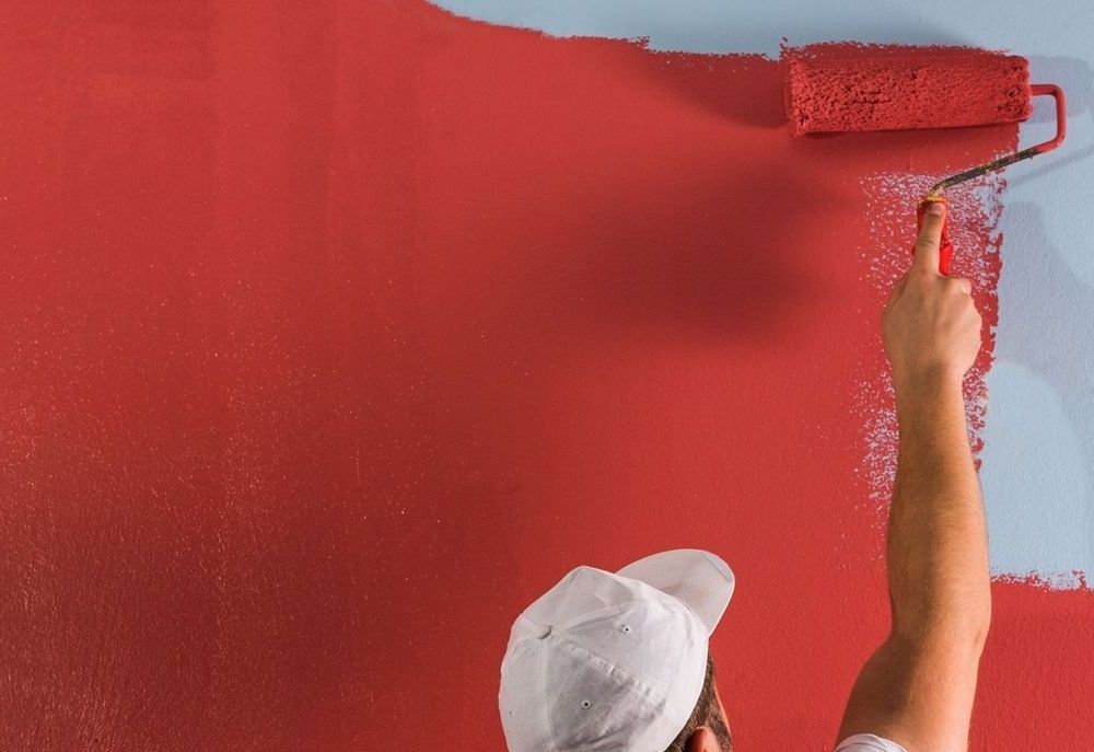 Maler streicht eine Wand rot